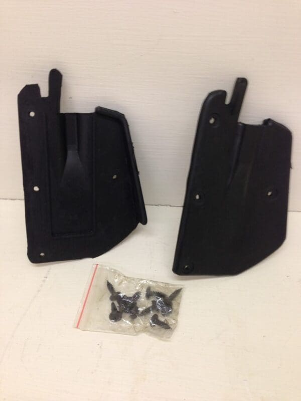 A pair of black plastic mud flaps with hardware.