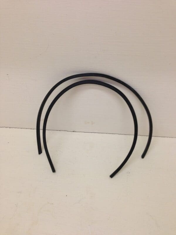 A pair of black rubber headbands on top of a white wall.