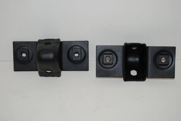 A pair of black plastic clips attached to the side of a wall.