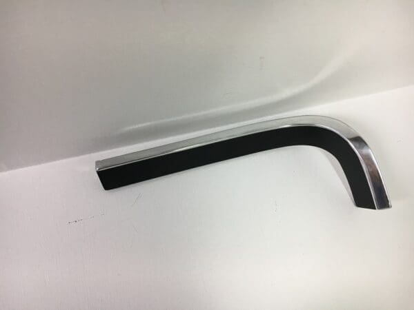 A bent piece of black rubber on the side of a white wall.