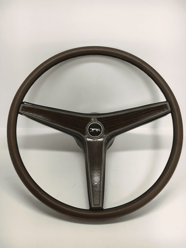 A steering wheel with the center of it in front of a white wall.