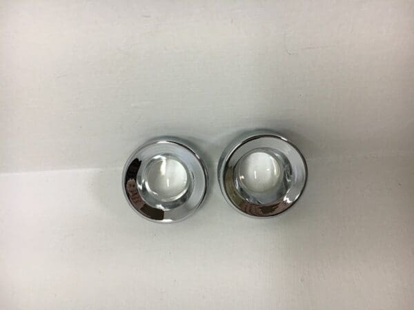 A pair of chrome knobs on the side of a bathroom wall.