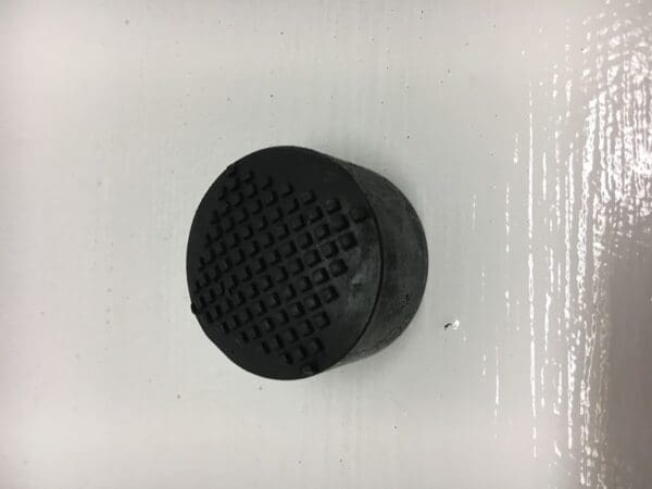 A black rubber object sitting on top of a white surface.