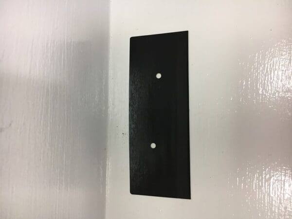 A black wall plate with two holes in it.