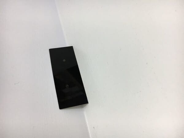 A black remote control sitting on top of a white surface.