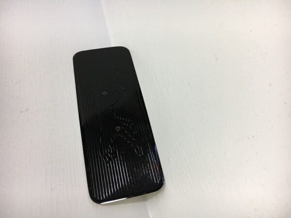 A black cell phone sitting on top of a table.