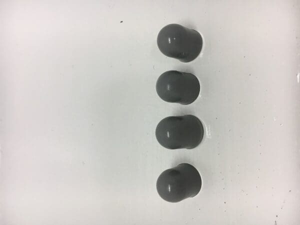 Four balls of gray rubber sit on a white surface.