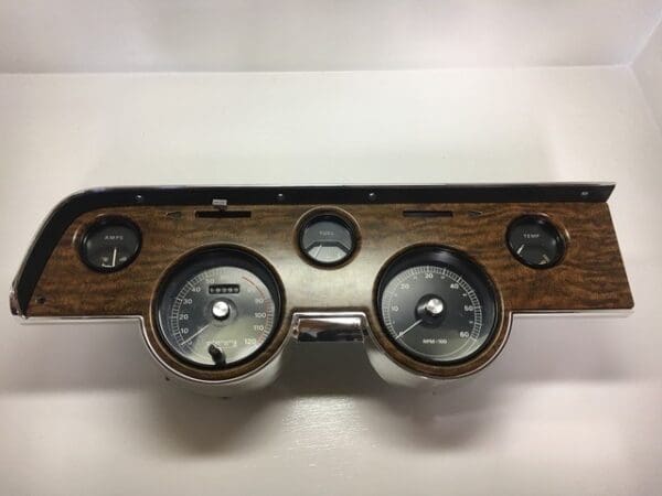 A wooden dashboard with four gauges and one meter.