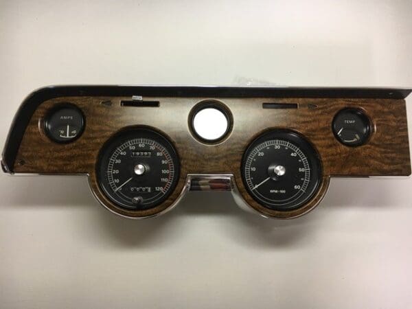 A wooden dashboard with three gauges and one meter.