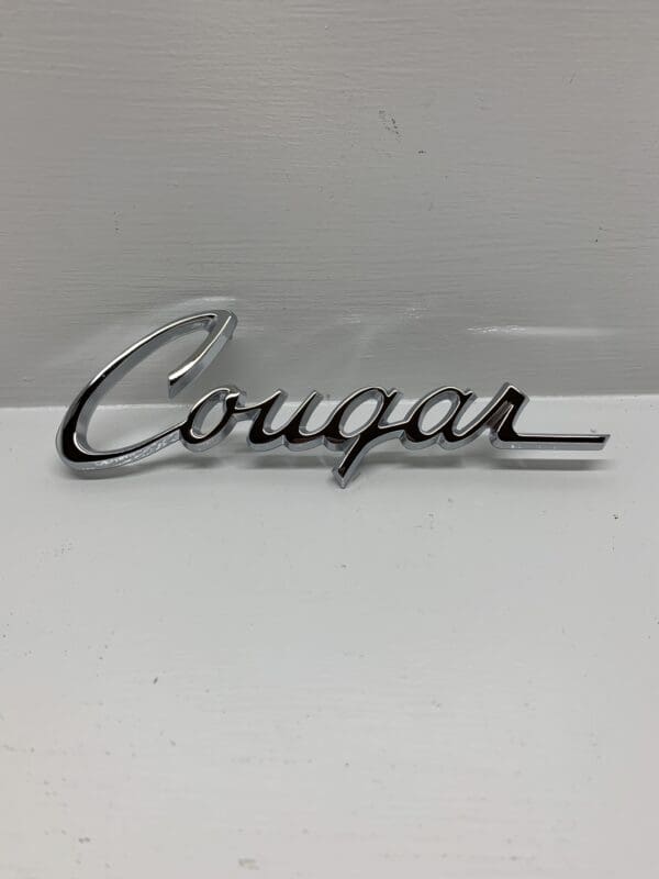 A chrome cougar emblem on the side of a car.