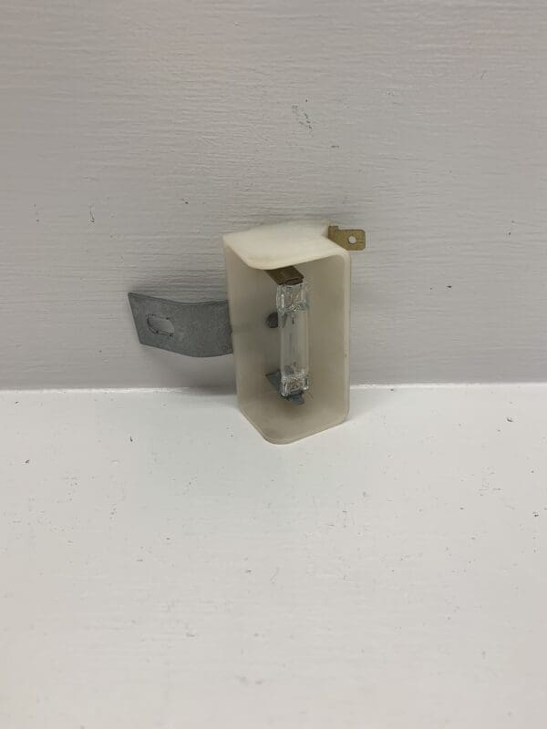 A white wall mounted device with a metal clip.